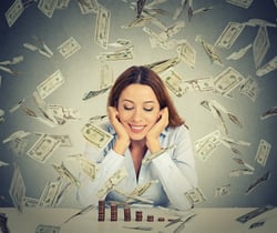 Excited happy young woman sitting at table with growing stack of coins under a money rain isolated on gray wall background. Positive emotions financial success luck good economy concept.jpeg